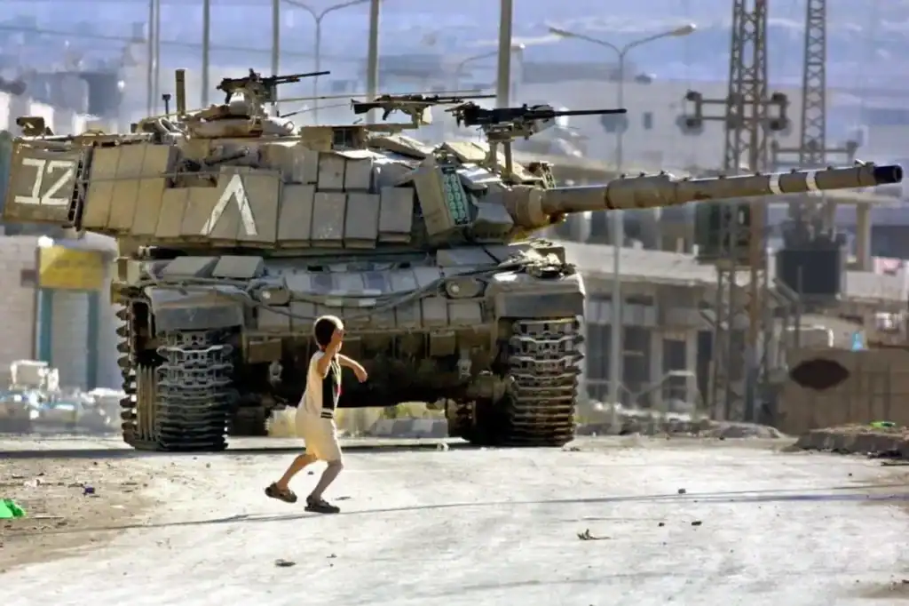 Palestinian child throws rock at IOF tank.