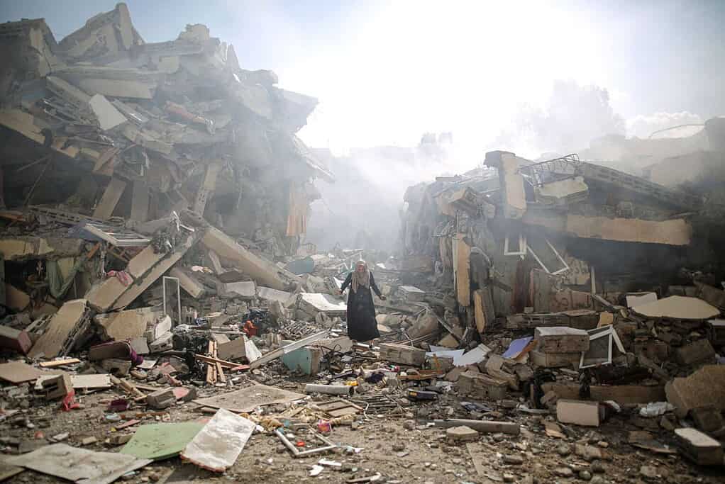 Palestinian woman standing in Gaza rubble from post Oct 7 Genocide
